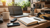 Notebook, laptop, voice recorder, phone, and work gloves on a warm desk, representing recovery writing and rebuilding work.